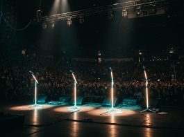 A conceptual image of an empty stage with illuminated microphone stands symbolizing a tour support act exodus.