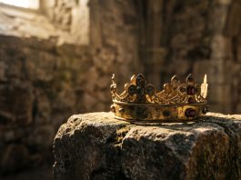 A cinematic gold crown resting on a stone surface.