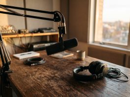 A professional studio microphone and headphones on a desk in warm light.