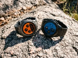 Two rugged smartwatches placed on a desert rock under intense direct sunlight.
