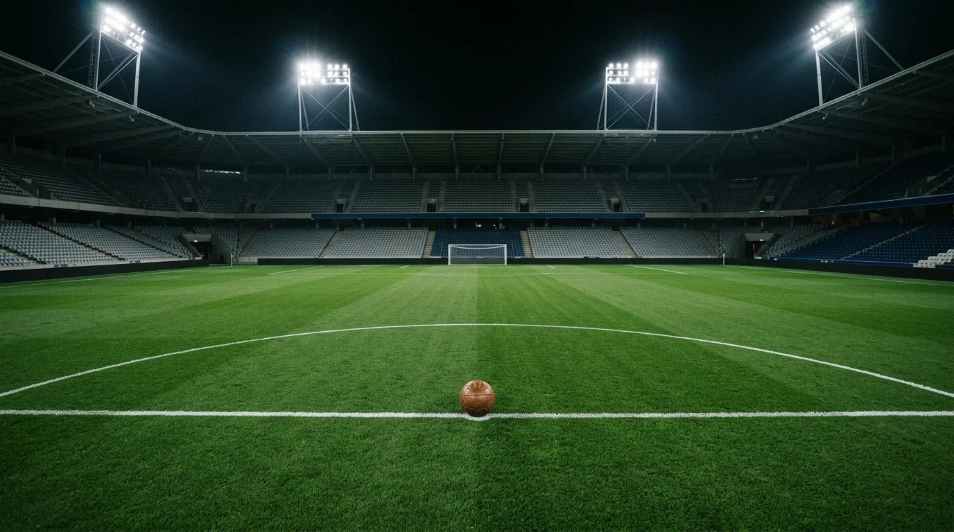 An empty football stadium at night under bright lights.
