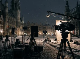 A cinematic film set in a snowy urban environment with silhouettes of production equipment.