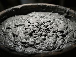 A conceptual shot of thick gray clay bubbling under a spotlight.