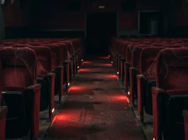 Conceptual image of an empty dark movie theater with red lighting and spider webs.
