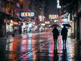 An atmospheric night scene in an Asian city with neon lights reflecting on the pavement.