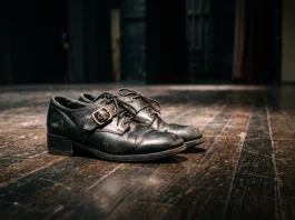A pair of Irish dance shoes on a dark stage under a spotlight.