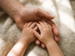 Conceptual image of an adult hand holding two children's hands