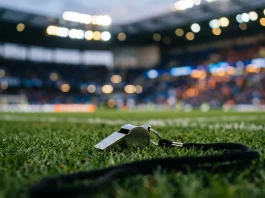 A whistle resting on a soccer pitch field representing a change in coaching leadership.